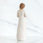 White ceramic figurine of a woman with a textured dress on a white background