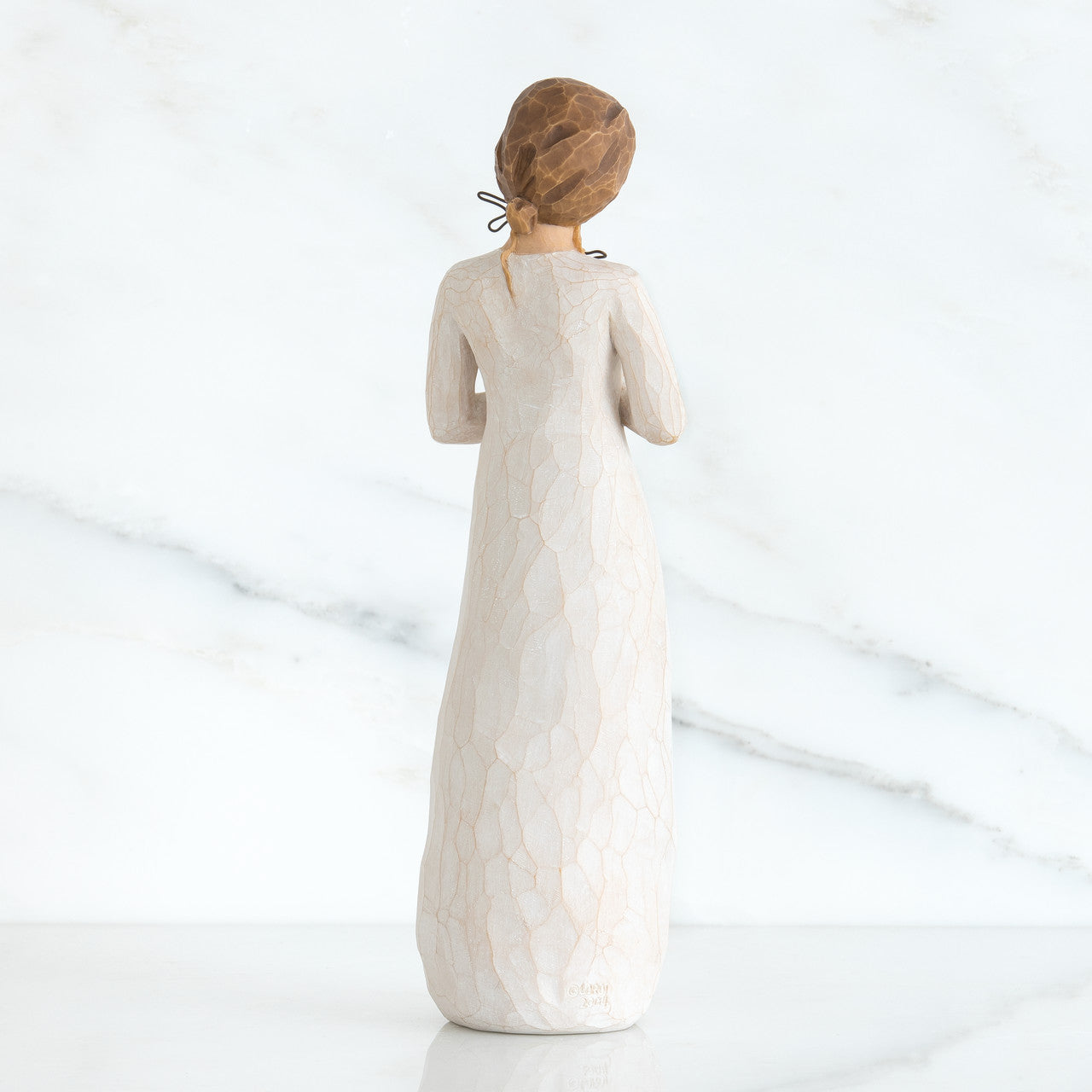White ceramic figurine of a woman with a textured dress on a white background