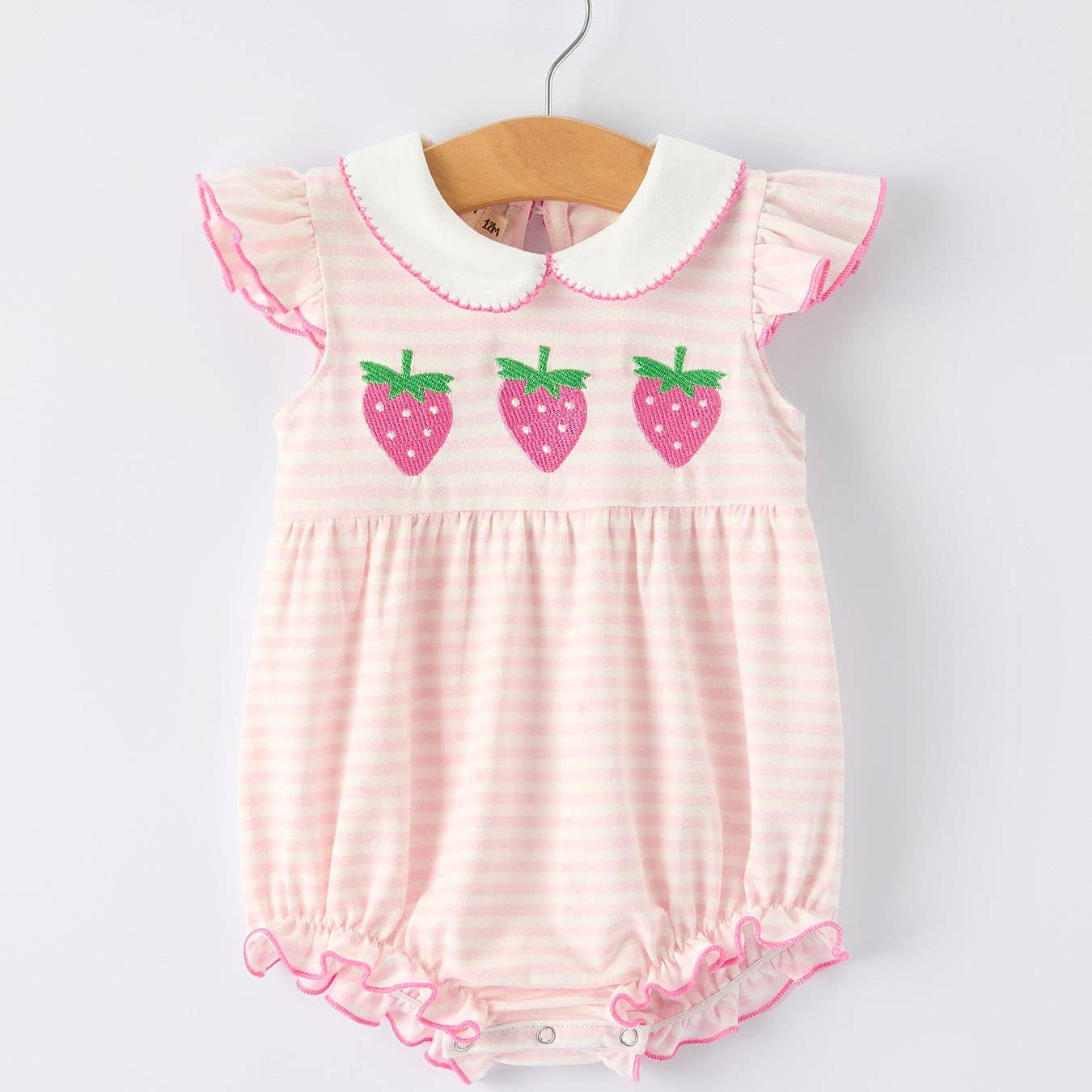 Pink baby romper with strawberry design on a white background