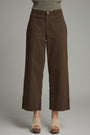 Brown wide-leg pants worn with a gray sweater on a plain background