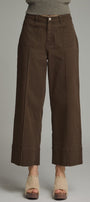Brown wide-leg pants worn with a gray sweater on a plain background