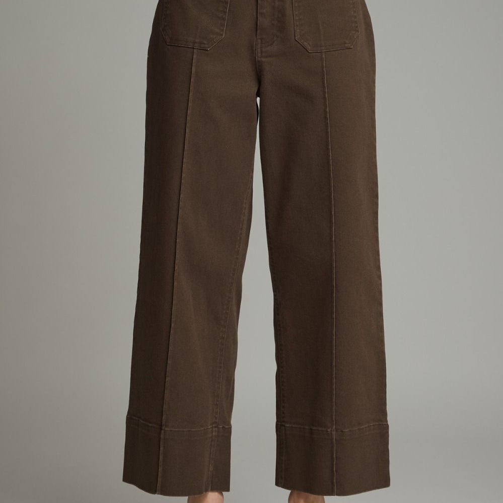 Brown wide-leg pants worn with a gray sweater on a plain background