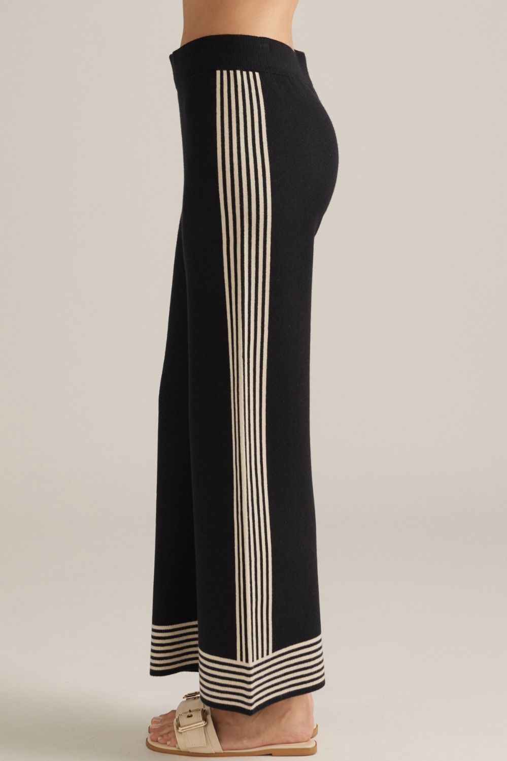Black flared pants with tall cream vertical stripe panel and striped hem border.