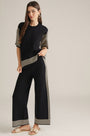 Black wide-leg pants with cream vertical stripes and striped hem border, elastic waist.