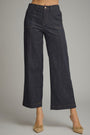 A model wearing dark indigo wide-leg cropped denim pants with beige pointed-toe flats, shown from the waist down against a neutral gray studio background.