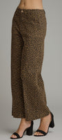 A person wearing leopard-print wide-leg cropped pants with black heeled sandals, shown from the waist down against a plain light gray studio background.