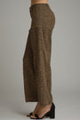 A person wearing leopard-print wide-leg pants and black heeled sandals, shown from the waist down against a plain light gray studio background.