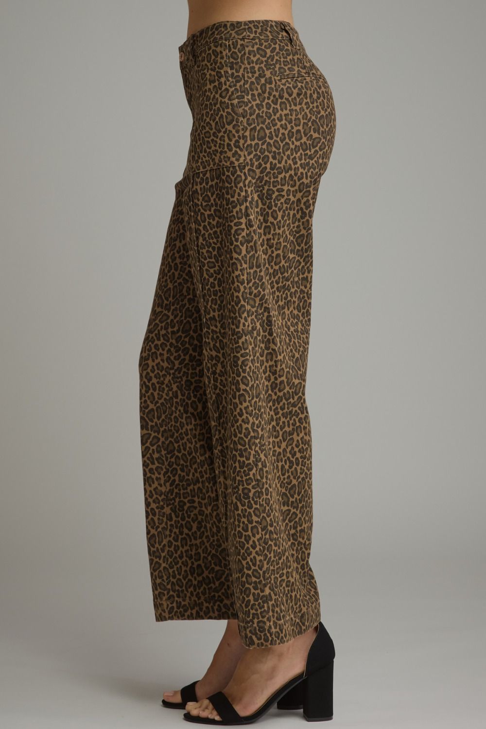 A person wearing leopard-print wide-leg pants and black heeled sandals, shown from the waist down against a plain light gray studio background.