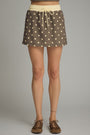 Brown polka dot skirt worn by a person on a gray background