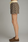 Brown polka dot shorts worn by a person on a gray background