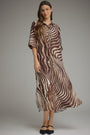 A woman modeling a brown and beige zebra-print midi shirt dress with three-quarter sleeves, paired with black flats, against a solid gray studio background.