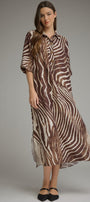 A woman modeling a brown and beige zebra-print midi shirt dress with three-quarter sleeves, paired with black flats, against a solid gray studio background.
