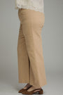 A person shown from the waist down wearing beige wide-leg cropped pants, a white lace-trim top, and brown heeled mules against a plain gray studio background.