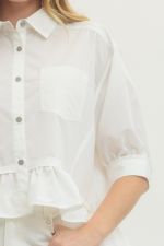 Close-up of a white shirt with rolled-up sleeves worn by a person.