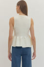 Woman wearing a white sleeveless top and blue jeans on a plain background