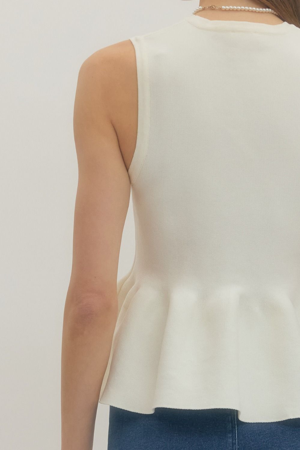 White sleeveless top worn by a person on a plain background