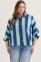 Woman wearing a blue and white striped shirt with a plaid skirt against a neutral background