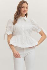 Woman wearing a white blouse with ruffled details on a plain background