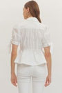 Person wearing a white blouse and pants against a plain background