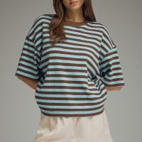Woman wearing a striped shirt and shorts on a gray background