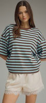 Woman wearing a striped shirt and shorts on a gray background