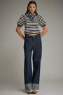 Woman wearing a striped shirt and blue jeans against a plain background