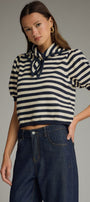 Woman wearing a striped sweater and jeans against a gray background