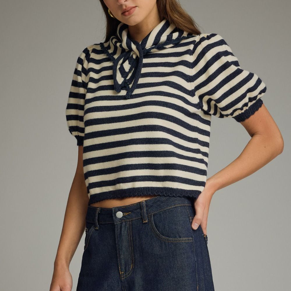 Woman wearing a striped sweater and jeans against a gray background
