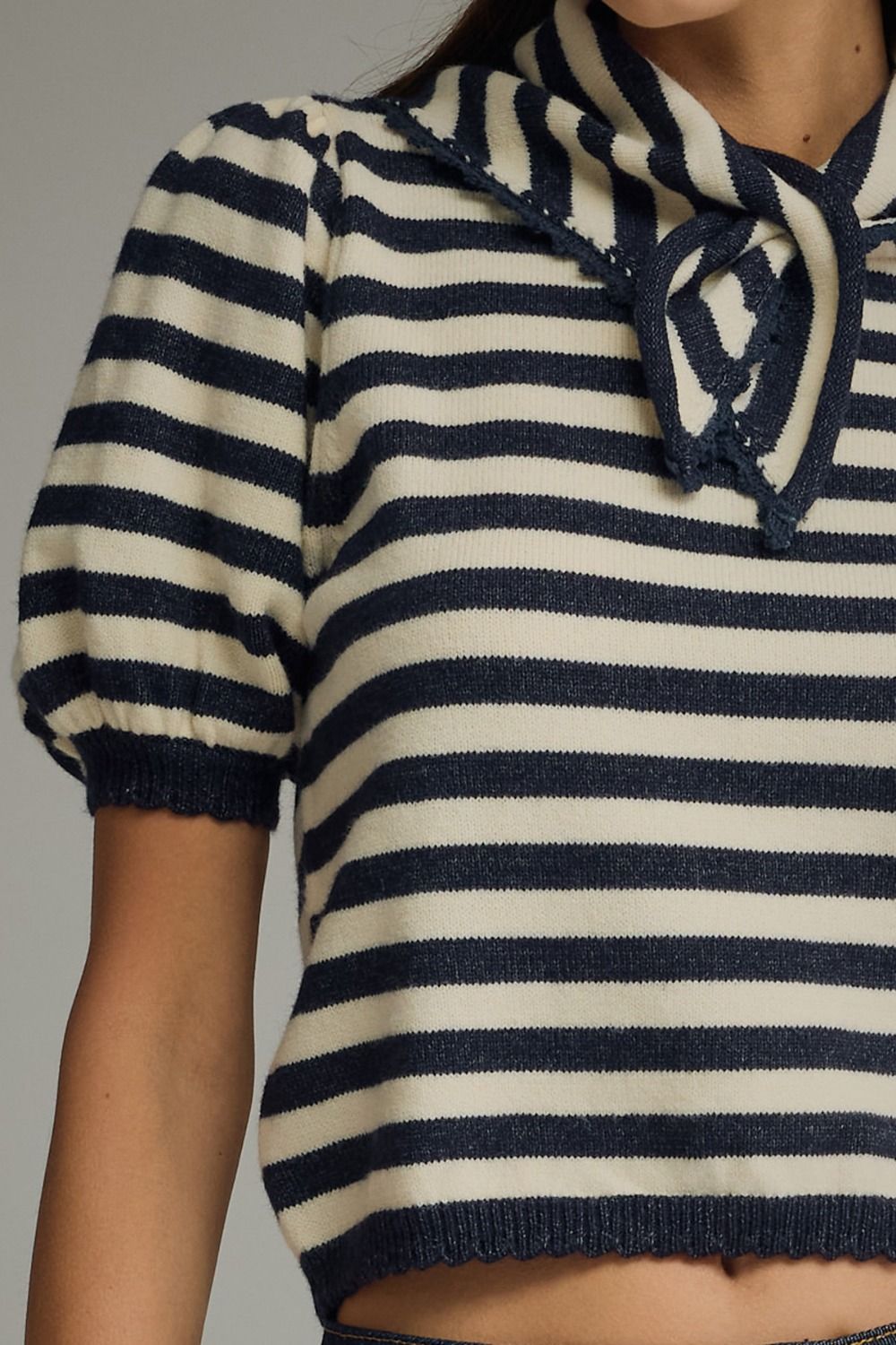 Navy and white striped sweater with a lace-up detail on a neutral background