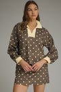 Woman wearing a polka dot dress with a plain background