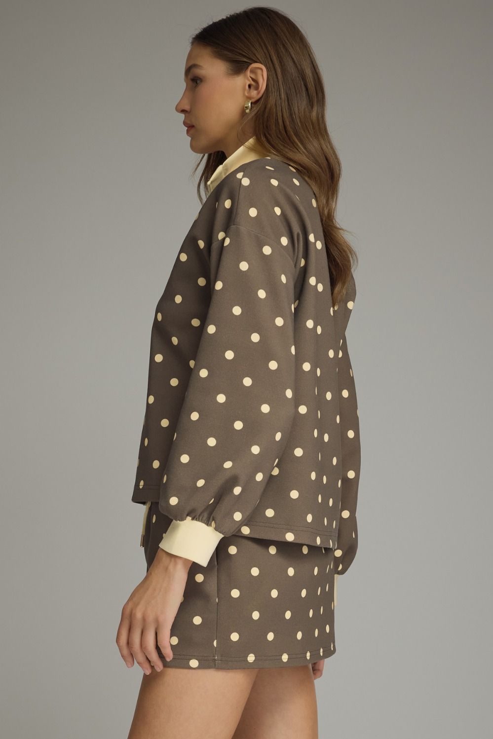 Woman wearing a brown polka dot outfit against a gray background