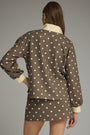 Woman wearing a brown polka dot outfit with a plain background