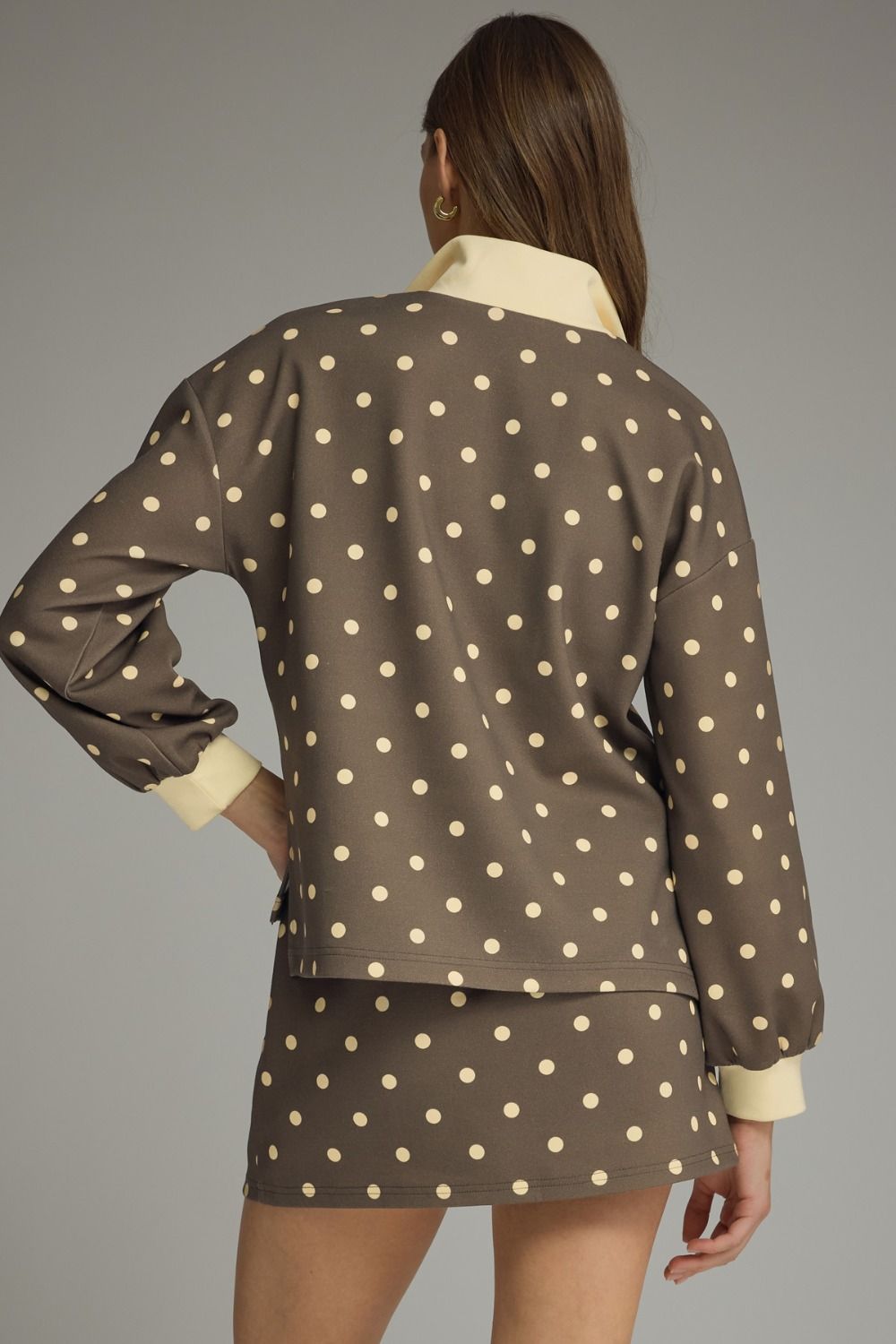 Woman wearing a brown polka dot outfit with a plain background