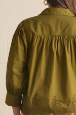 An olive green long-sleeve blouse with a gathered, smocked bodice and delicate lace embroidery along the hem, shown from the back.