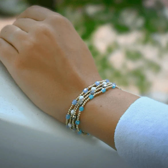 Close-up of a wrist wearing multiple beaded bracelets with a blurred natural background