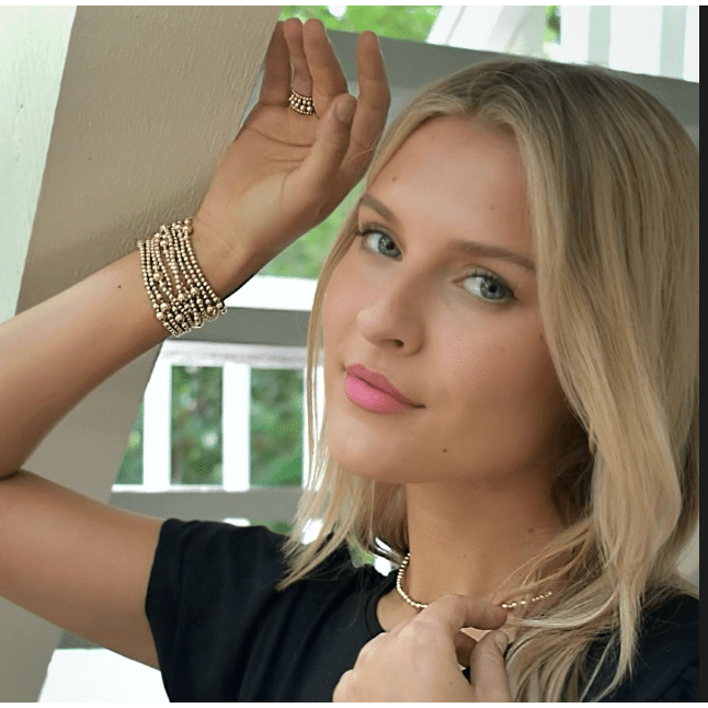 Woman with blonde hair and pink lipstick posing indoors