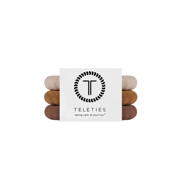 A set of four Teleties hair care towels in neutral earthy tones, stacked vertically with a white paper band featuring the black Teleties logo and brand name.