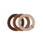 Three textured fabric baby teething rings in dark brown, medium brown, and cream, overlapping on a solid white background. The cream ring features a small silver metal brand tag with the word 'TELL'.