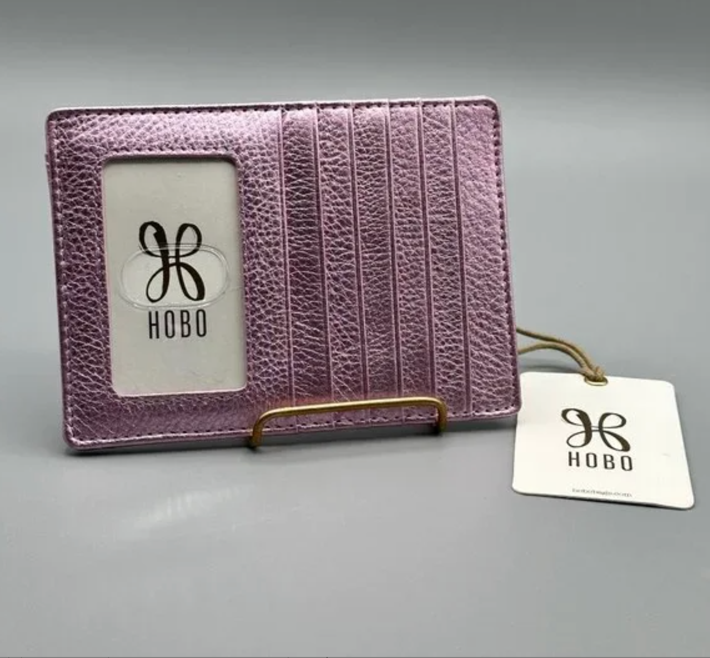 Pink leather cardholder with 'Hobo' branding on a gray background