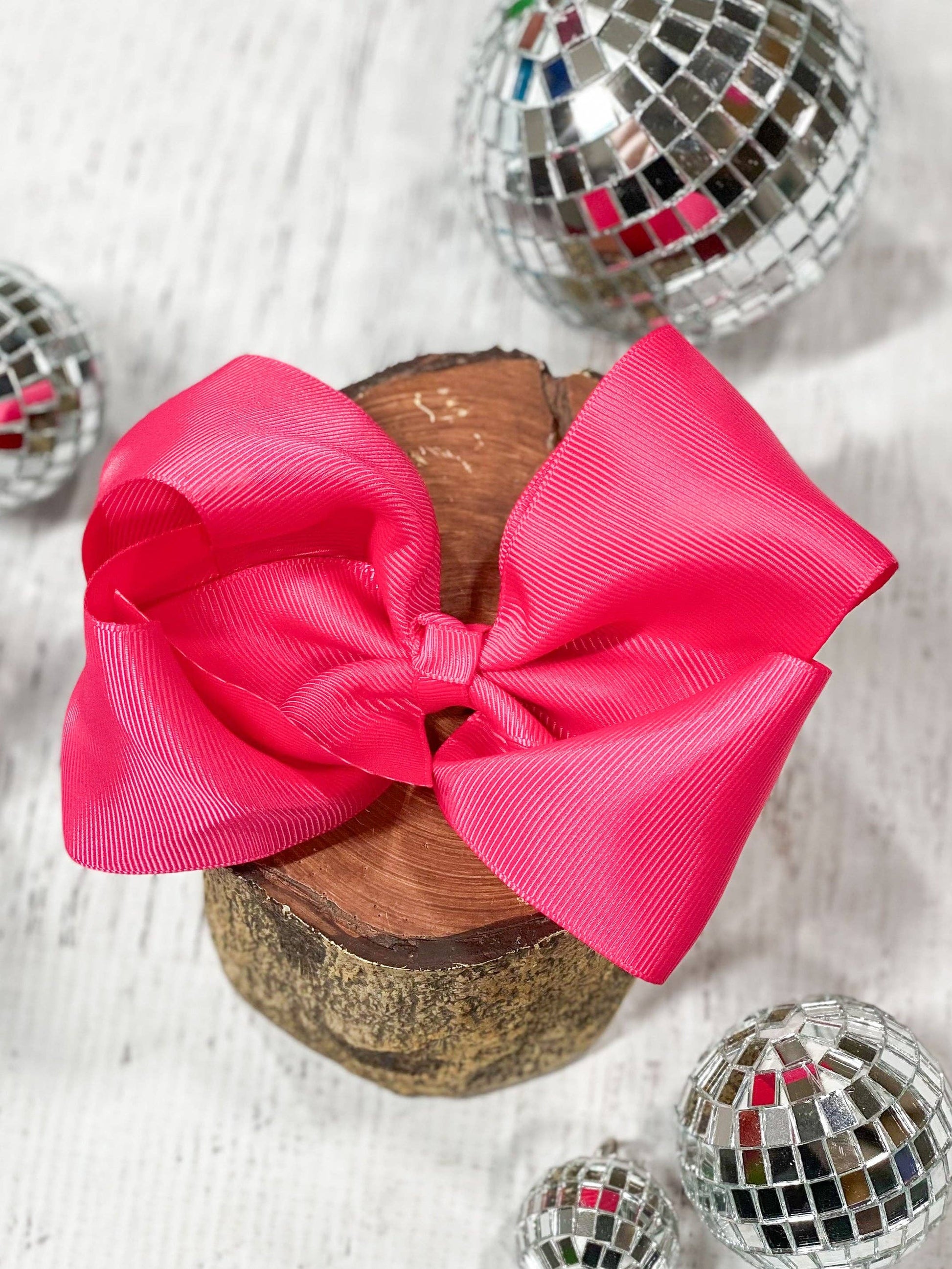 Large pink bow on a wooden block with disco balls around