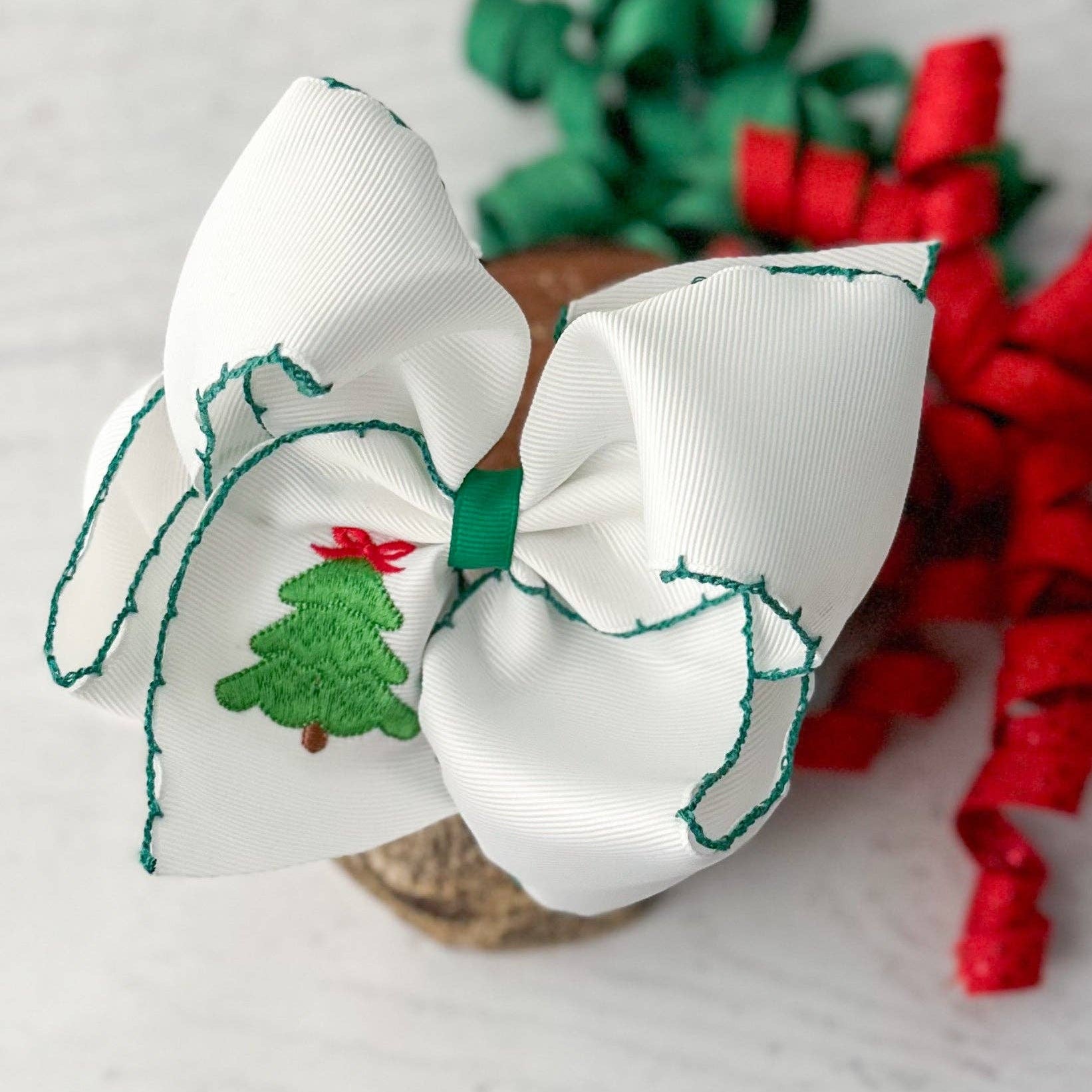 White hair bow with Christmas tree design on a light background