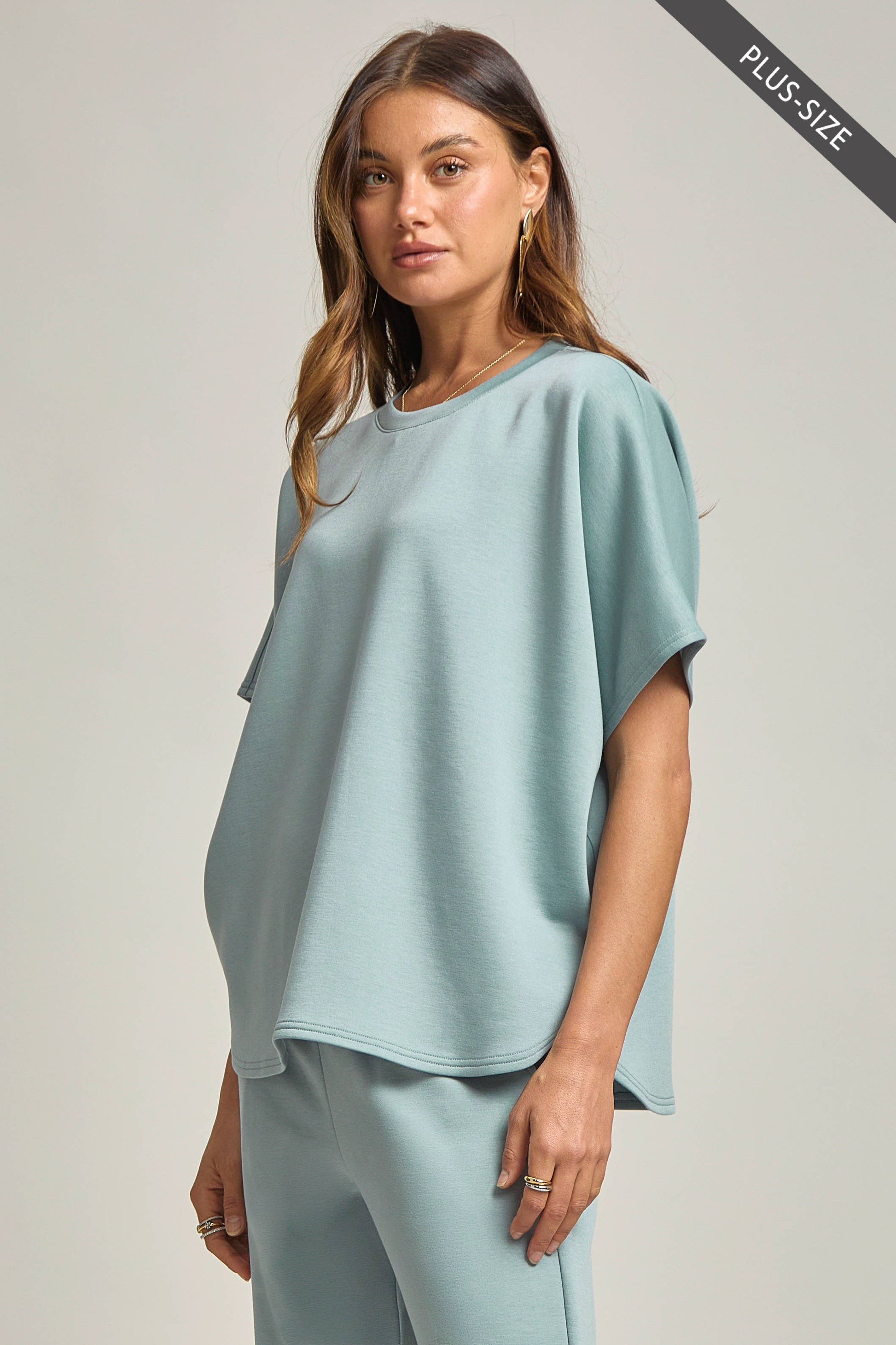 Woman wearing a light blue plus-size top and pants on a plain background