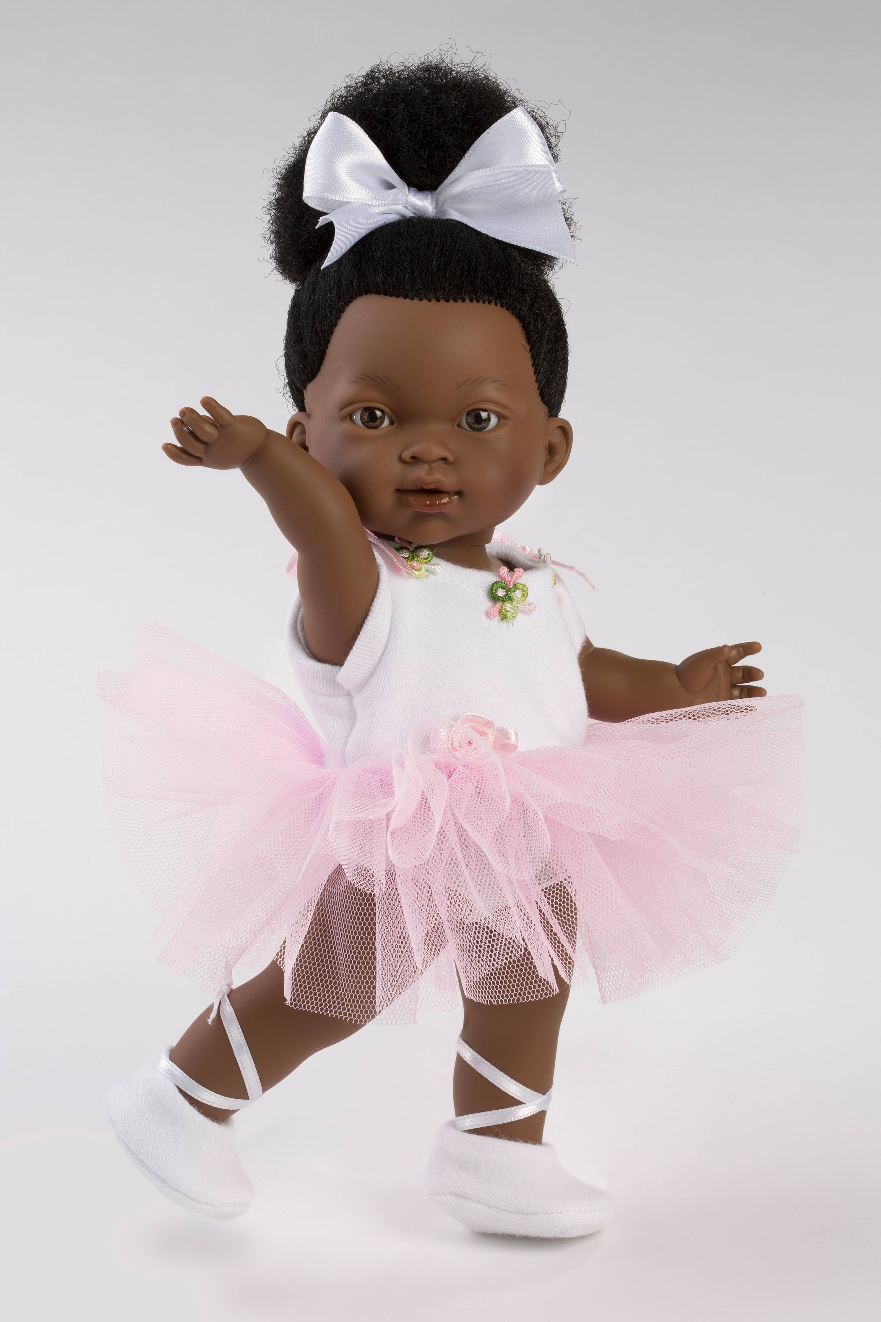 Doll in a ballet outfit with a pink tutu and white shoes on a plain background
