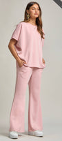 Woman wearing a pink outfit with wide-leg pants on a plain background