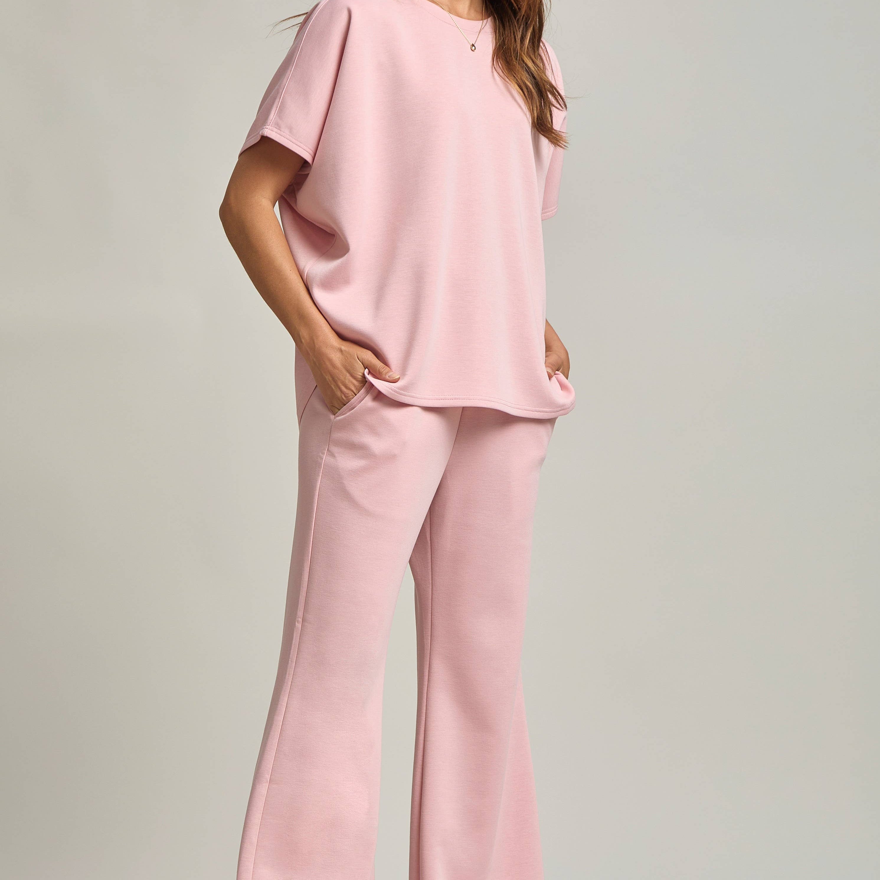 Woman wearing a pink outfit with wide-leg pants on a plain background