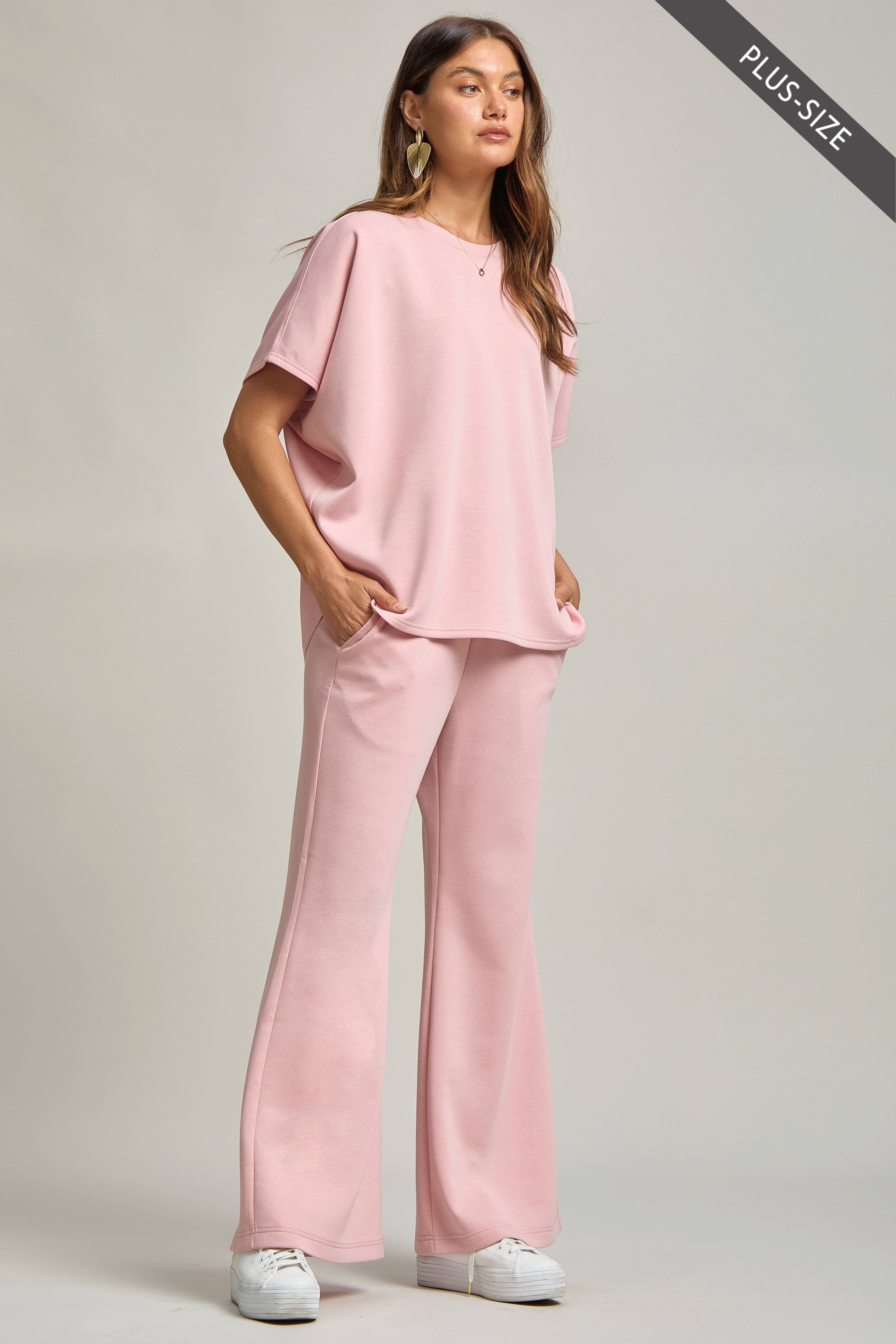 Woman wearing a pink outfit with wide-leg pants on a plain background