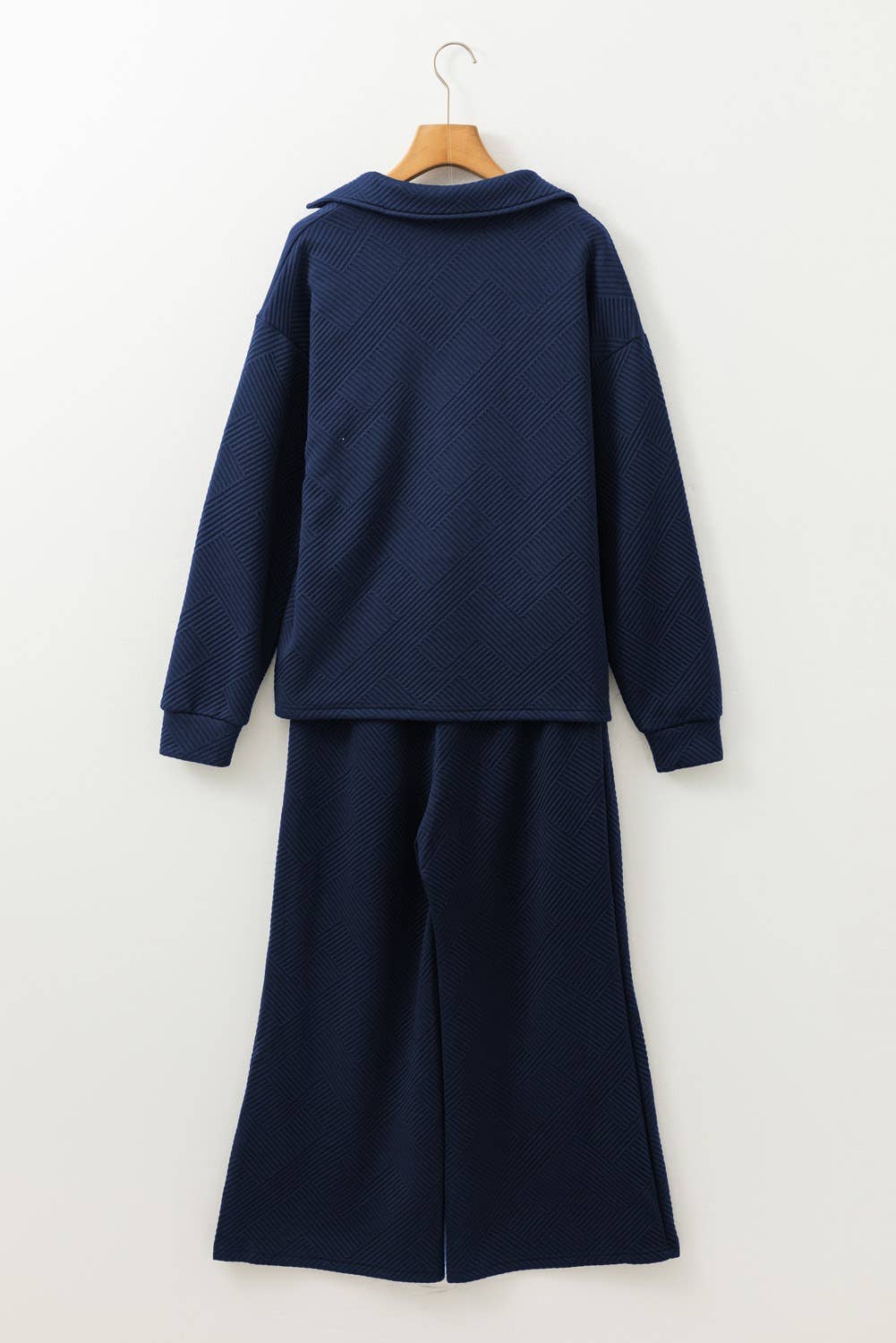Navy blue outfit with a long-sleeve top and wide-leg pants on a hanger against a white background