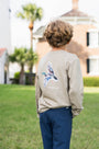 Person wearing a beige sweatshirt with a colorful design on the back, standing outdoors.