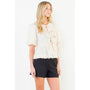 Woman wearing a white blouse with ruffles and black shorts on a white background