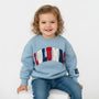 Child wearing a light blue sweatshirt with colorful letters on a white background